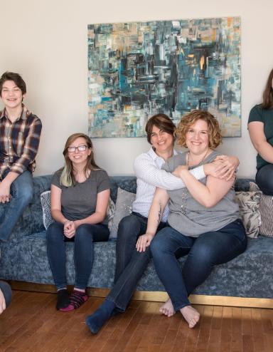 A smiling family of six in a living room. Partially obscured.