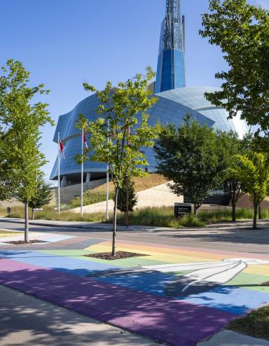 Pride flag pedestrian crosswalk across from the Canadian Museum for Human Rights. Partially obscured.