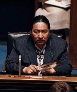 A man sitting in front of a microphone holding an eagle feather